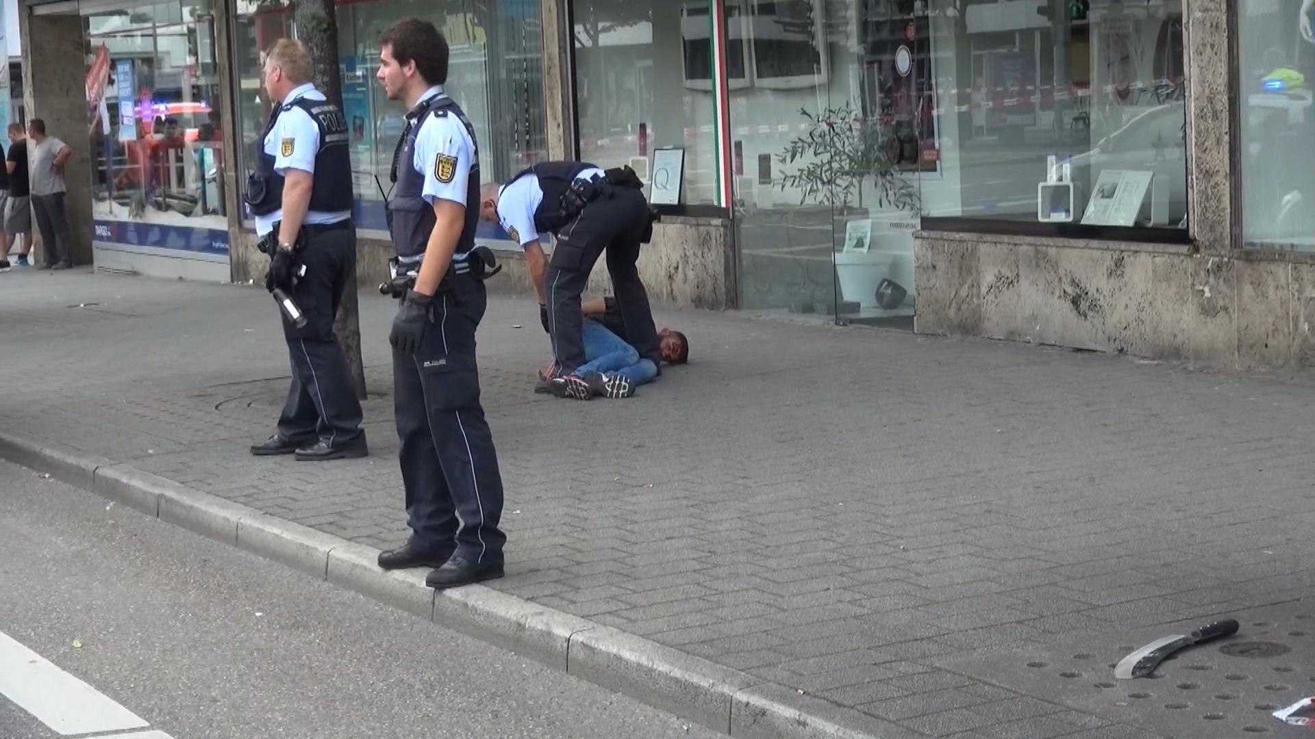 Police officers arrest a man close to a machete, front right, after an attack in Reutilingen, Germany, July 24, 2016.