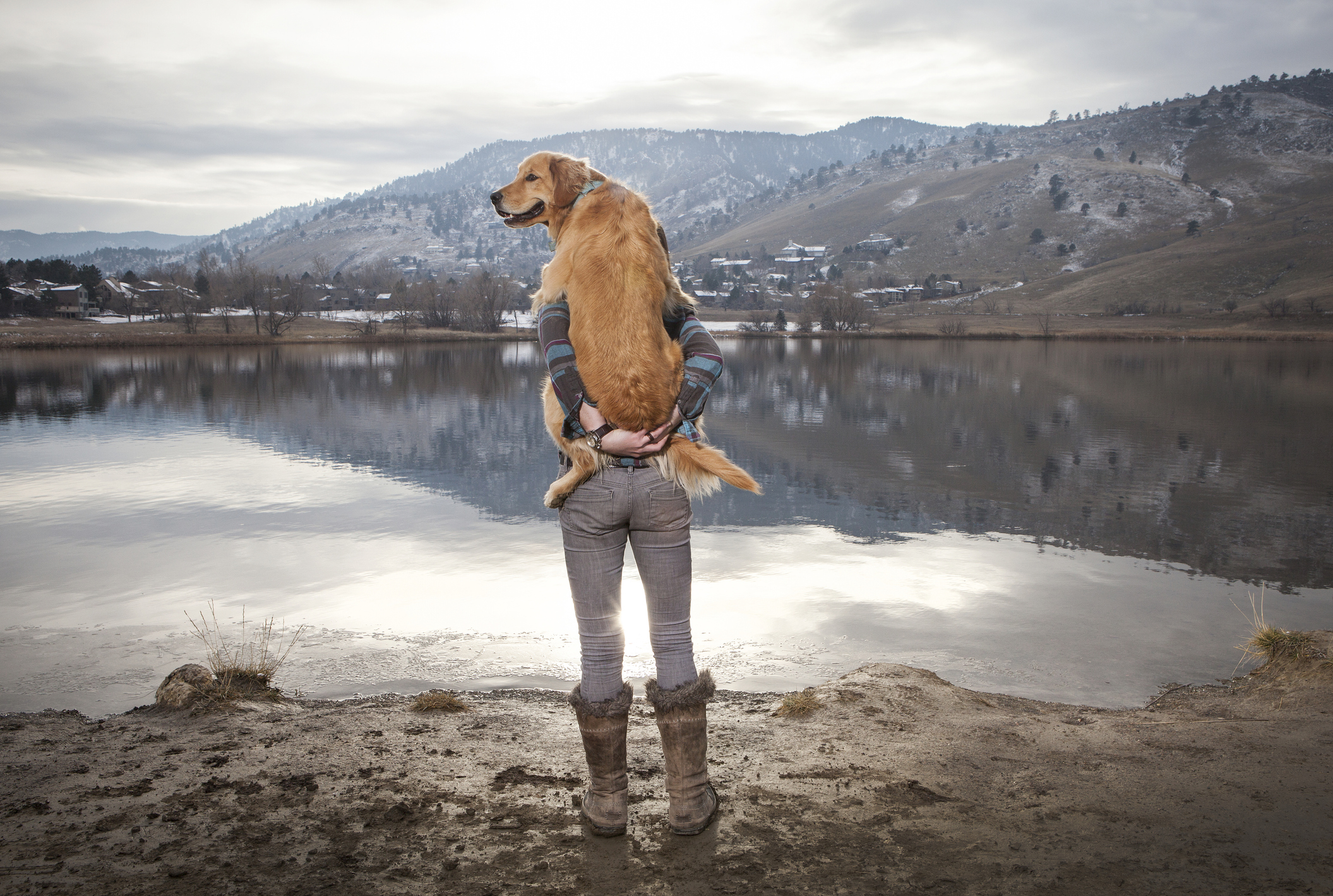 Woman holding her Golden Retriever at lake