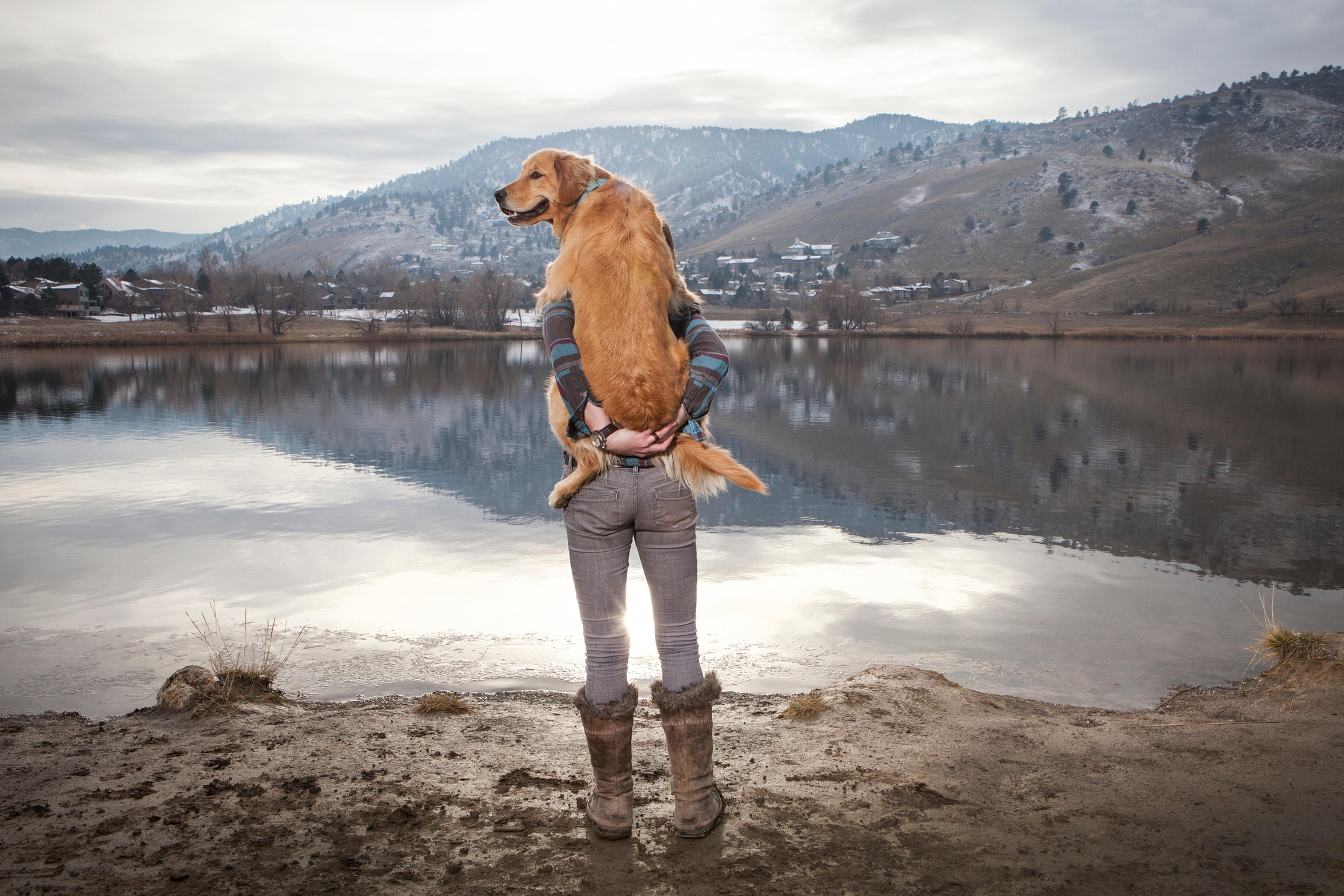 Woman holding her Golden Retriever at lake