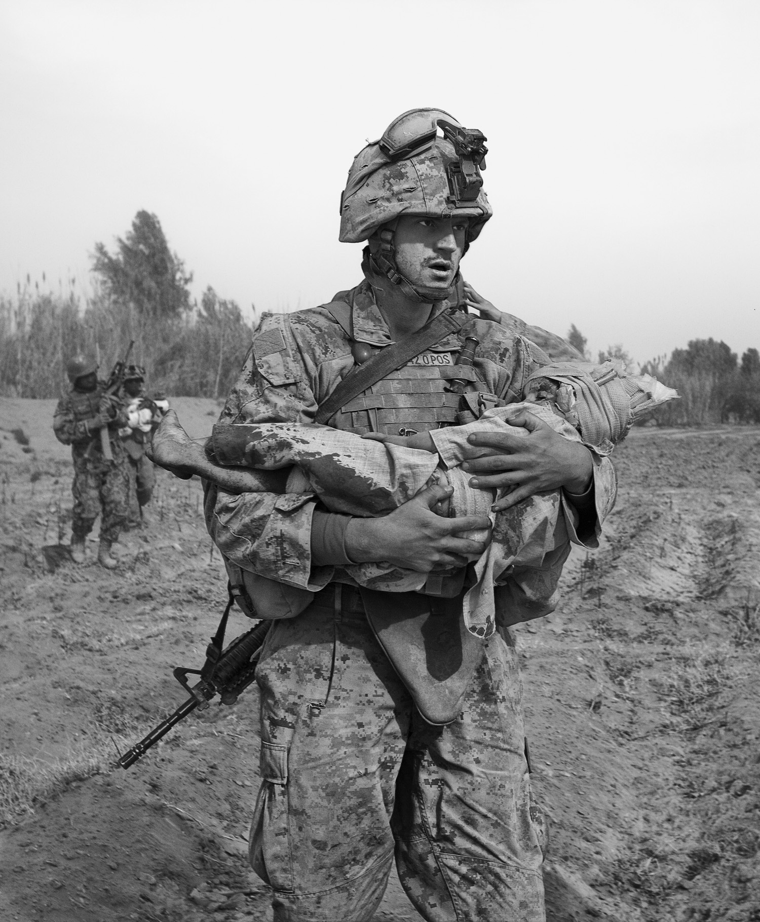 A Marine carries an Afghan child, one of two wounded by coalition aircraft during an air support mission.