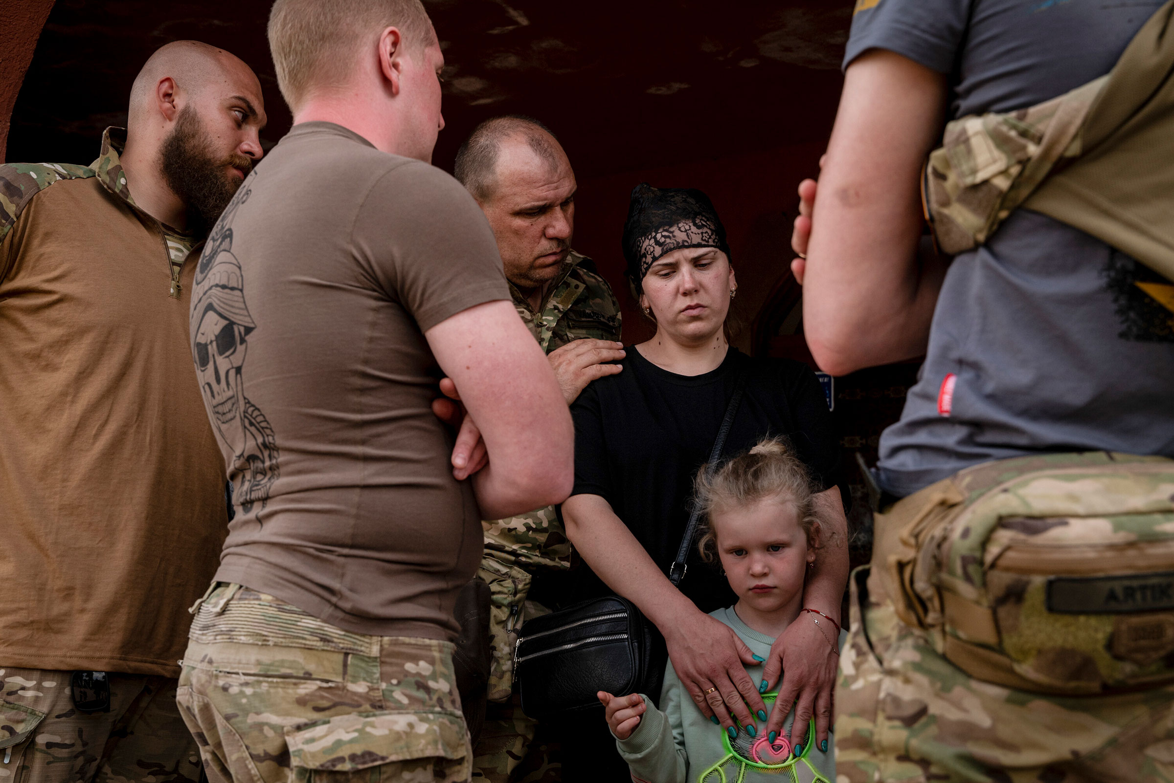 Ukrainian soldiers comforted Iryna Sharhorodska, and her daughter Sonia, following the funeral for her husband Sergeant Oleksandr Sharhorodskyi, on Sunday, May 21, 2023. (Nicole Tung/The New York Times)
