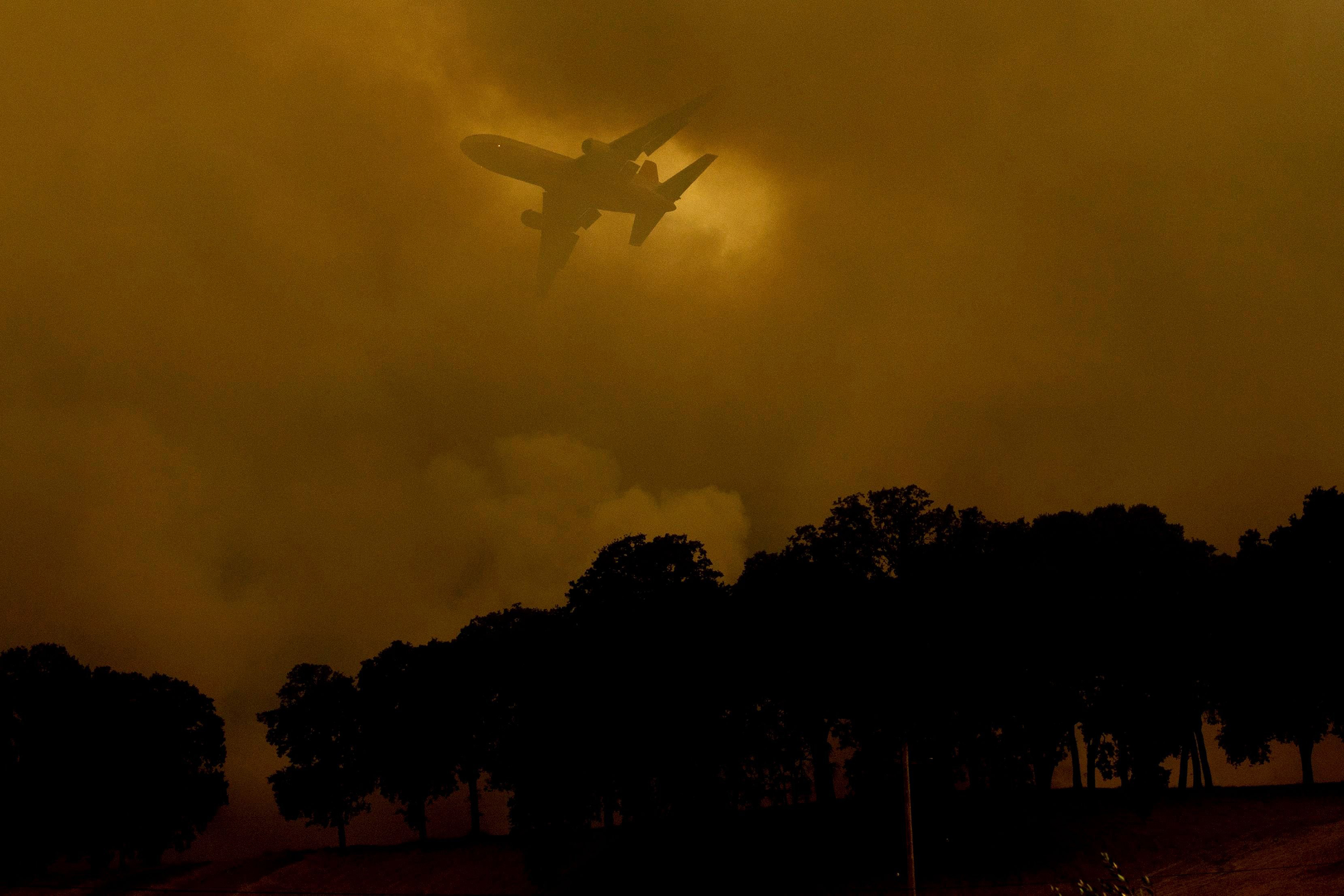 An air tanker passes behind a smoke plume while battling the River Fire in Lakeport, Calif., on July 30.