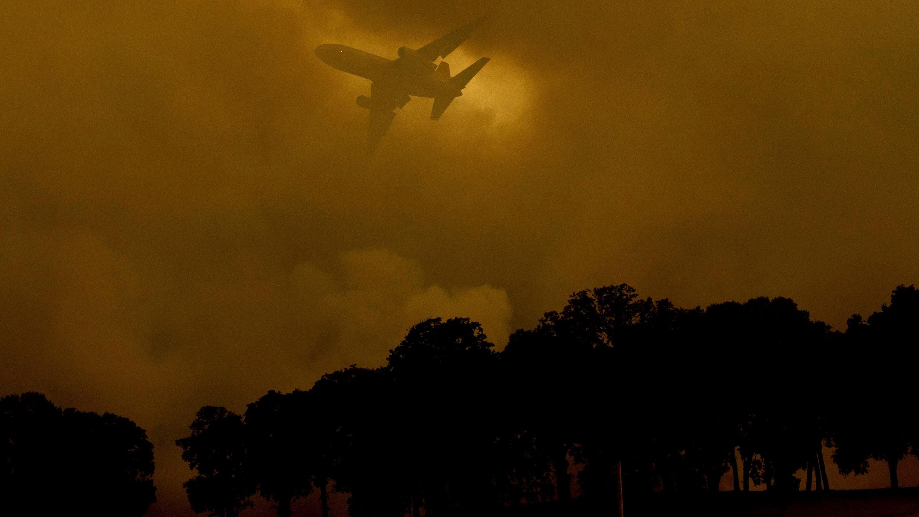 An air tanker passes behind a smoke plume while battling the River Fire in Lakeport, Calif., on July 30.