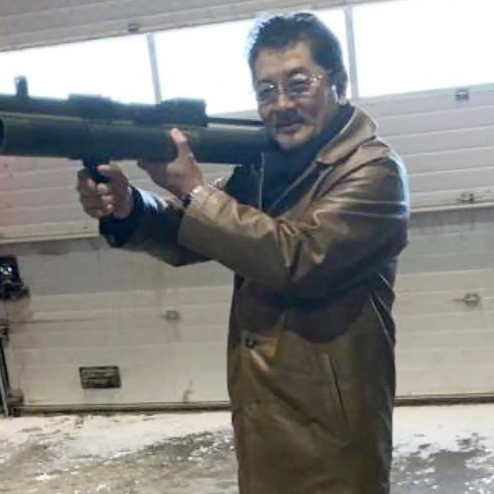 Takeshi Ebisawa poses with a rocket launcher during a meeting with an informant at a warehouse in Copenhagen