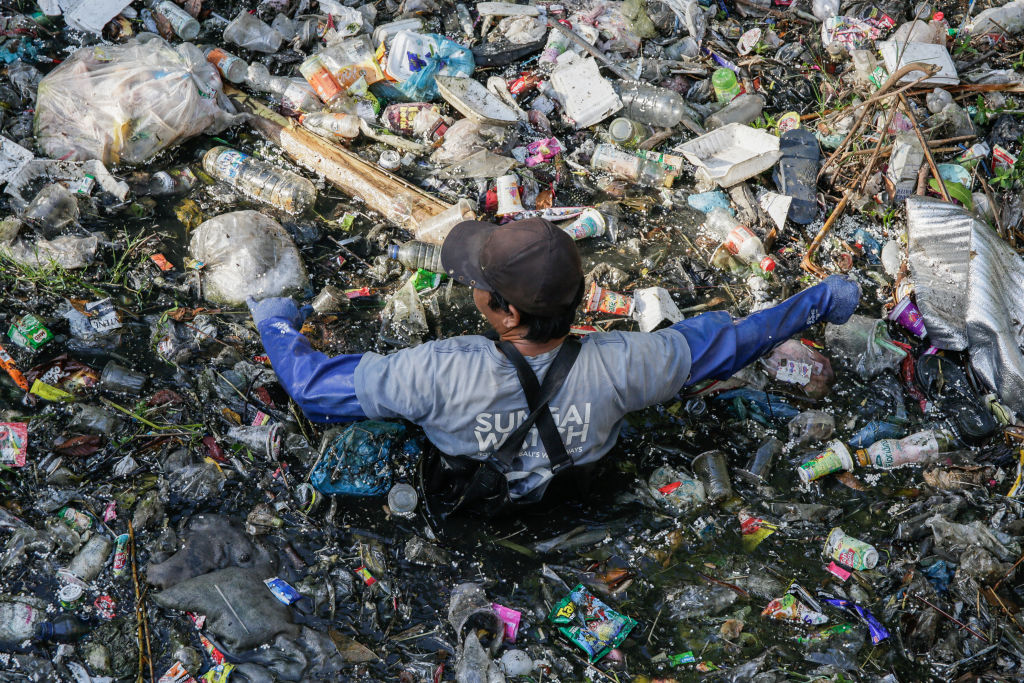 Environmental activists unclogs plastic trash on polluted river before being excavated for sorting and recycling in Denpasar, Bali, Indonesia on Aug. 19, 2023.