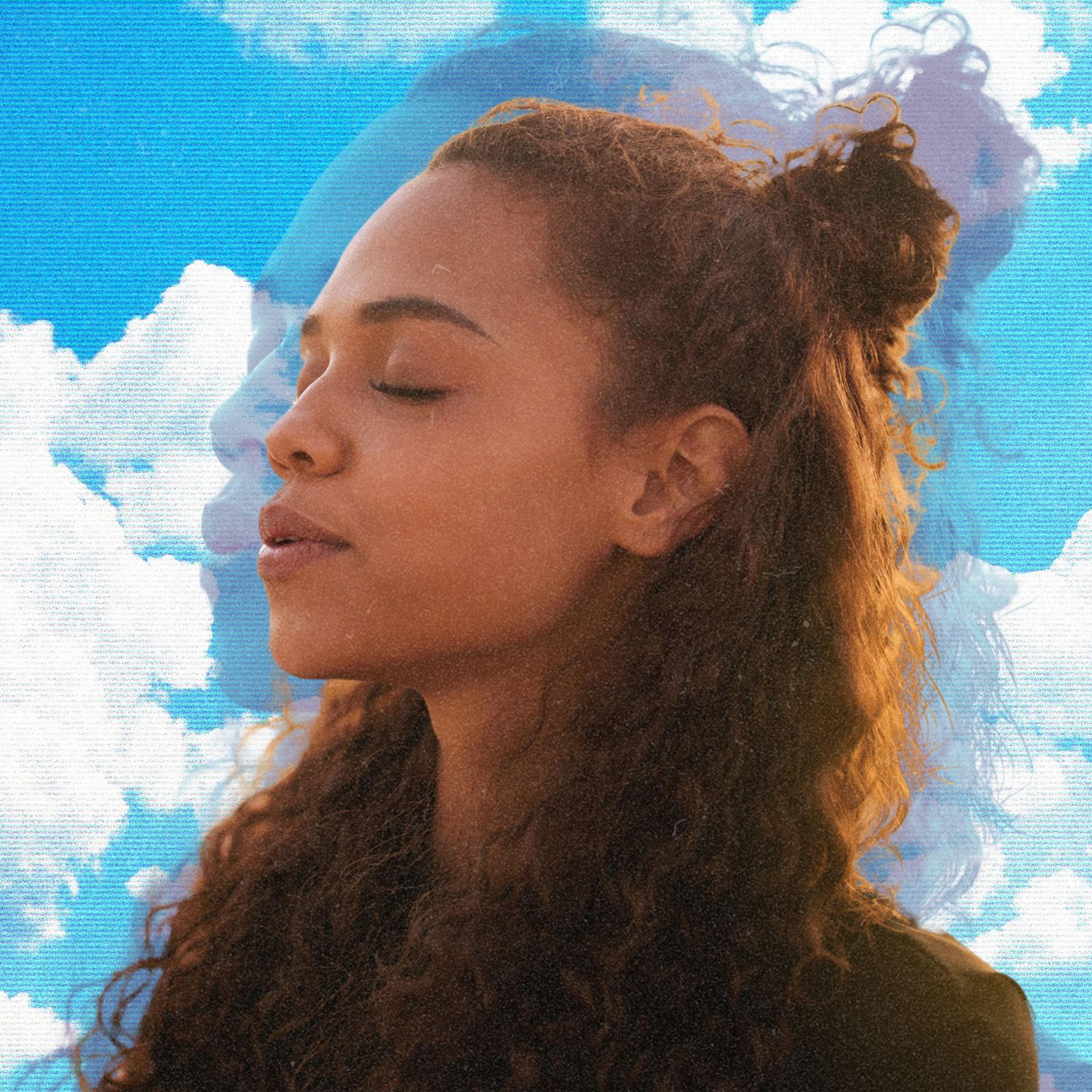 A woman taking a breath with clouds behind her