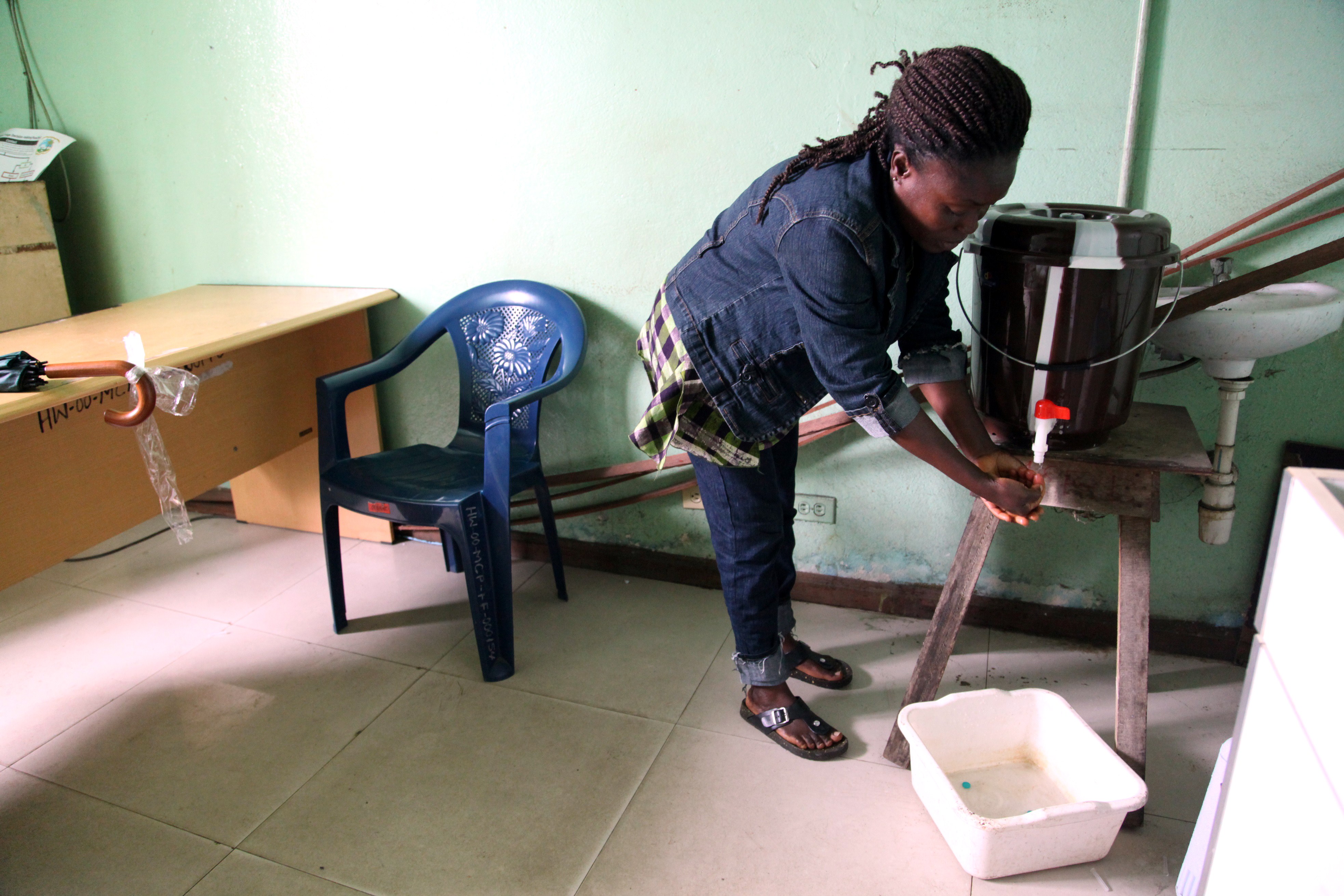 Washing hands with chlorine water, as this woman does at a public health center on July 31 in Monrovia, Liberia, is among the few ways to protect against Ebola, since there are no vaccines or treatments against infection