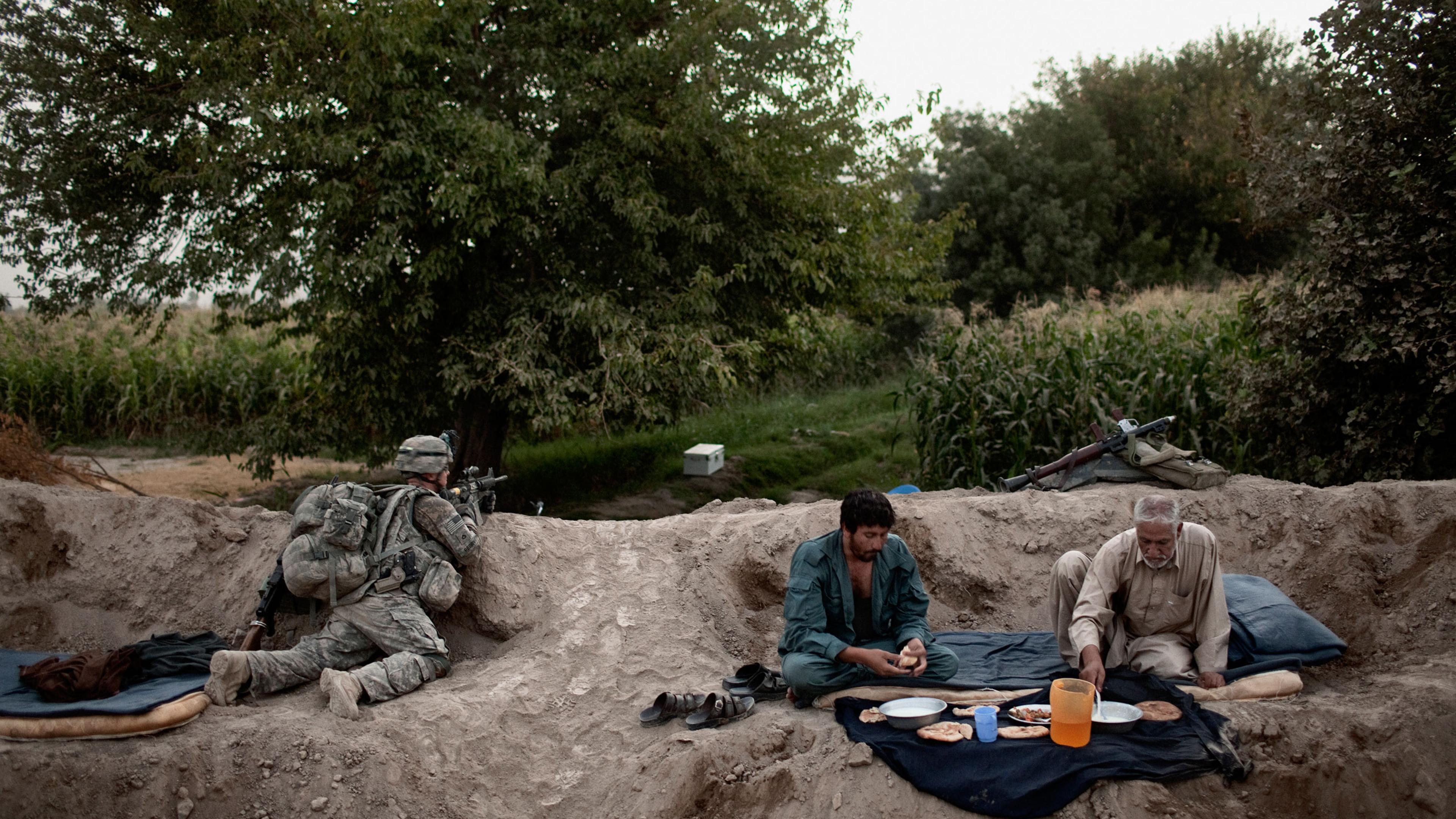 Afghan National Police broke their fast for Iftar during Ramadan while a soldier from the 504th U.S. Military Police Battalion provided security in the Mehlajat area of Kandahar City, Afghanistan on September 6, 2010. Photo by Adam Ferguson